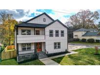 Two-story home with modern farmhouse design, featuring a bright orange door and landscaped lawn at 4562 Spring St, Acworth, GA 30101