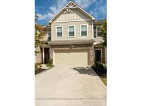 Two-story townhome with beige siding, brick accents, and a two-car garage at 5431 Cascade Sw Run, Atlanta, GA 30336