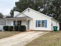 House exterior featuring a light-yellow vinyl siding, blue shutters, and a small front porch at 459 Eagles Crossing Cir, Riverdale, GA 30274