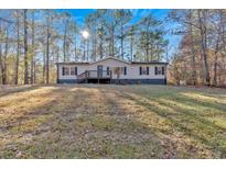 Single-story home with deck and large yard, wooded lot at 157 Reynolds Rd, Bowdon, GA 30108