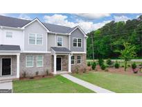 Two-story townhome with gray and brick exterior, landscaping, and walkway at 491 Reflection Dr # 33, Stockbridge, GA 30281