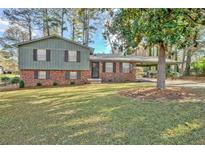 Brick ranch house with green siding, covered carport, and a spacious yard at 7546 Palmetto Way, Riverdale, GA 30274