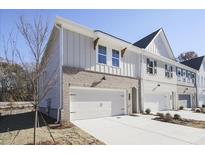Two-story townhome with brick and siding exterior, attached garage, and landscaping at 913 Agate Ln, Lawrenceville, GA 30043