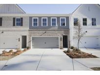 Three-unit townhome building, featuring gray and white exteriors, two-car garages, and landscaping at 909 Agate Ln, Lawrenceville, GA 30043