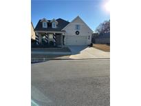 Two-story house with light brick exterior, two-car garage, and landscaping at 204 Floral Valley Dr, Woodstock, GA 30188