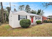 Brick ranch home with red door, landscaping, and a spacious yard at 2671 Tilson Rd, Decatur, GA 30032