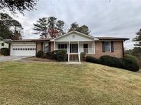 Brick ranch house with attached garage and landscaped lawn at 5227 Manitu Sw Ct, Lilburn, GA 30047