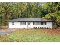 Newly renovated ranch home with white exterior, landscaping, and a spacious yard at 7058 Lakeview Ln, Atlanta, GA 30360