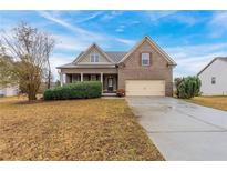 Brick and siding two-story house with attached garage and manicured lawn at 1032 Richmond Place Way, Loganville, GA 30052