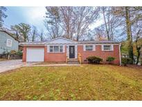 Brick ranch house with a landscaped lawn and attached garage at 1410 Willow Dr, Riverdale, GA 30296