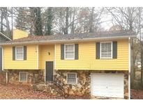 Ranch-style home with yellow siding, stone accents, and attached garage at 1593 Cherry Hill Ln, Conyers, GA 30094