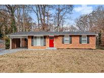Brick ranch house with red door, attached carport, and landscaped yard at 2707 Crescendo Nw Dr, Atlanta, GA 30318