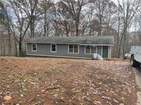 Charming single-story home with gray siding and a wooded front yard at 3930 Ridgeland Dr, Douglasville, GA 30135