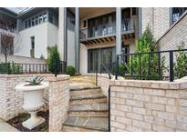 Stone steps lead up to a patio with a brick wall and iron railing at 90 Sheridan Dr, Atlanta, GA 30305