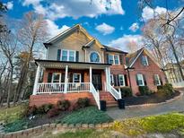 Two-story brick home with a large front porch and landscaped yard at 3658 Clark Hill Way, Buford, GA 30519