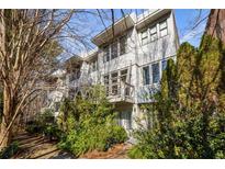 Modern white three-story townhome with multiple windows and a balcony at 9129 Selborne Ln, Chattahoochee Hills, GA 30268