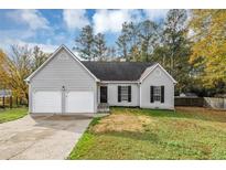 Gray house with two-car garage and landscaped yard at 1299 Paddocks Way, Powder Springs, GA 30127