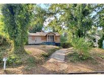 Boarded-up home with overgrown yard and concrete walkway at 244 Morris Brown Nw Ave, Atlanta, GA 30314