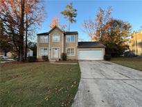 Two-story house with a tan exterior, attached garage, and landscaping at 5830 Burdett Ridge, Atlanta, GA 30349