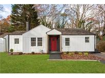 Charming white cottage with red door, landscaped lawn, and mature trees at 1349 Lockhaven Sw Cir, Atlanta, GA 30311