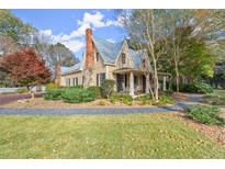 Charming two-story home with a front porch, rocking chairs, and a landscaped yard at 7865 Nesbit Ferry Rd, Sandy Springs, GA 30350