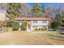 Two-story home with red door, shrubs, and green lawn at 633 Larchmont Nw Cir, Atlanta, GA 30318