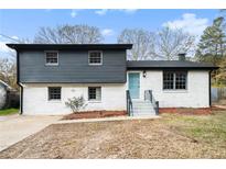 Charming two-story home with white brick exterior, dark gray siding, and teal front door at 6709 Londonderry Dr, Morrow, GA 30260