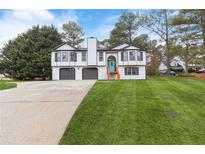 Charming two-story home with a bright blue door, gray two-car garage, and large green lawn at 934 Bay Ridge Dr, Lawrenceville, GA 30045