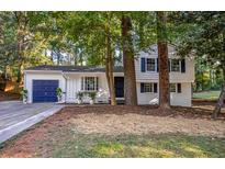Charming white two-story home nestled among trees with a blue garage door at 4001 Red Oak Dr, Atlanta, GA 30340