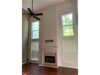 Living room featuring a fireplace, high ceilings, large windows, and wood floors at 635 Arncliffe Ct, Johns Creek, GA 30005