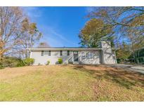 Charming single-story home with a grassy front yard and trees at 1347 Peggy Nw Ln, Conyers, GA 30012