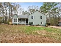 Charming two-story home with a green exterior, surrounded by trees at 412 Ladora Dr, Dallas, GA 30157