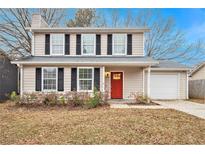 Two-story house with beige siding, red door, and attached garage at 2329 Wilkins Cv, Decatur, GA 30035