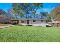 Ranch style home with white brick exterior, red door, and landscaped lawn at 1933 Glen Echo Dr, Decatur, GA 30032