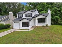 Newly renovated two-story house with a white exterior, black accents, and a landscaped lawn at 2023 Downs Pl, Lithonia, GA 30058