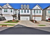 Attractive 3-story townhome with white siding, stone accents, and a 2-car garage at 257 Whitetail Cir, Canton, GA 30115