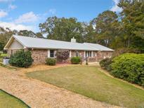 Brick ranch house with a metal roof, landscaping, and a large yard at 7312 Melrose Ct, Villa Rica, GA 30180