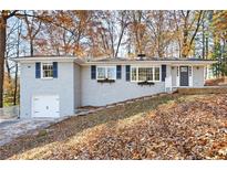 Newly renovated ranch home with gray brick exterior, updated landscaping, and attached garage at 3599 Dial Dr, Stone Mountain, GA 30083