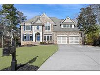 Brick two-story house with a three-car garage and landscaped lawn at 6315 Sturbridge Ln, Cumming, GA 30040