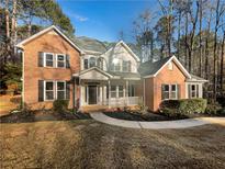 Brick two-story house with front porch and landscaped yard at 26 Ruisseau, Sharpsburg, GA 30277