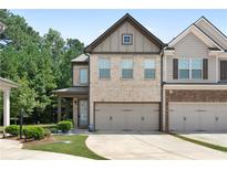 Two-story townhome with neutral brick exterior, two-car garage, and landscaping at 5531 Radford Loop, Fairburn, GA 30213