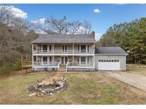 Two-story house with wraparound porch and attached garage, nestled on a spacious lot at 3076 Hopkins Rd, Powder Springs, GA 30127