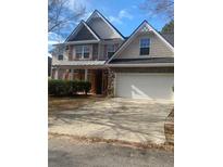 Two-story house with stone and shingle accents, a large driveway and manicured landscaping at 539 Greyhawk Way, Fairburn, GA 30213
