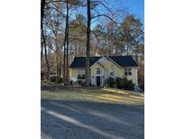 Yellow house with black roof, landscaping, and driveway at 3911 Howard Nw Dr, Kennesaw, GA 30152