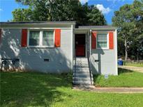 Gray brick ranch home with orange shutters, steps, and a landscaped lawn at 723 Casplan Sw St, Atlanta, GA 30310