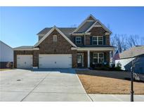 Two-story brick home with a three-car garage and landscaped yard at 7350 Rambling Vale, Cumming, GA 30028