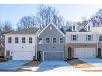 Two-story townhouses with gray and white brick exteriors, two-car garages, and landscaping at 147 Bluffington Way, Marietta, GA 30066