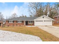 Brick ranch house with a two-car garage and landscaped yard at 1283 Woodleigh Sw Rd, Marietta, GA 30008