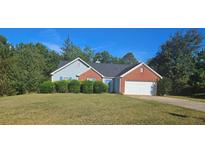 Brick and siding house with a 2-car garage and well-manicured lawn at 3009 River Garden Rd, Covington, GA 30016