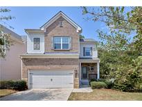 Two-story brick home with a white garage door and landscaping at 2169 Charcoal Ives Rd, Lawrenceville, GA 30045